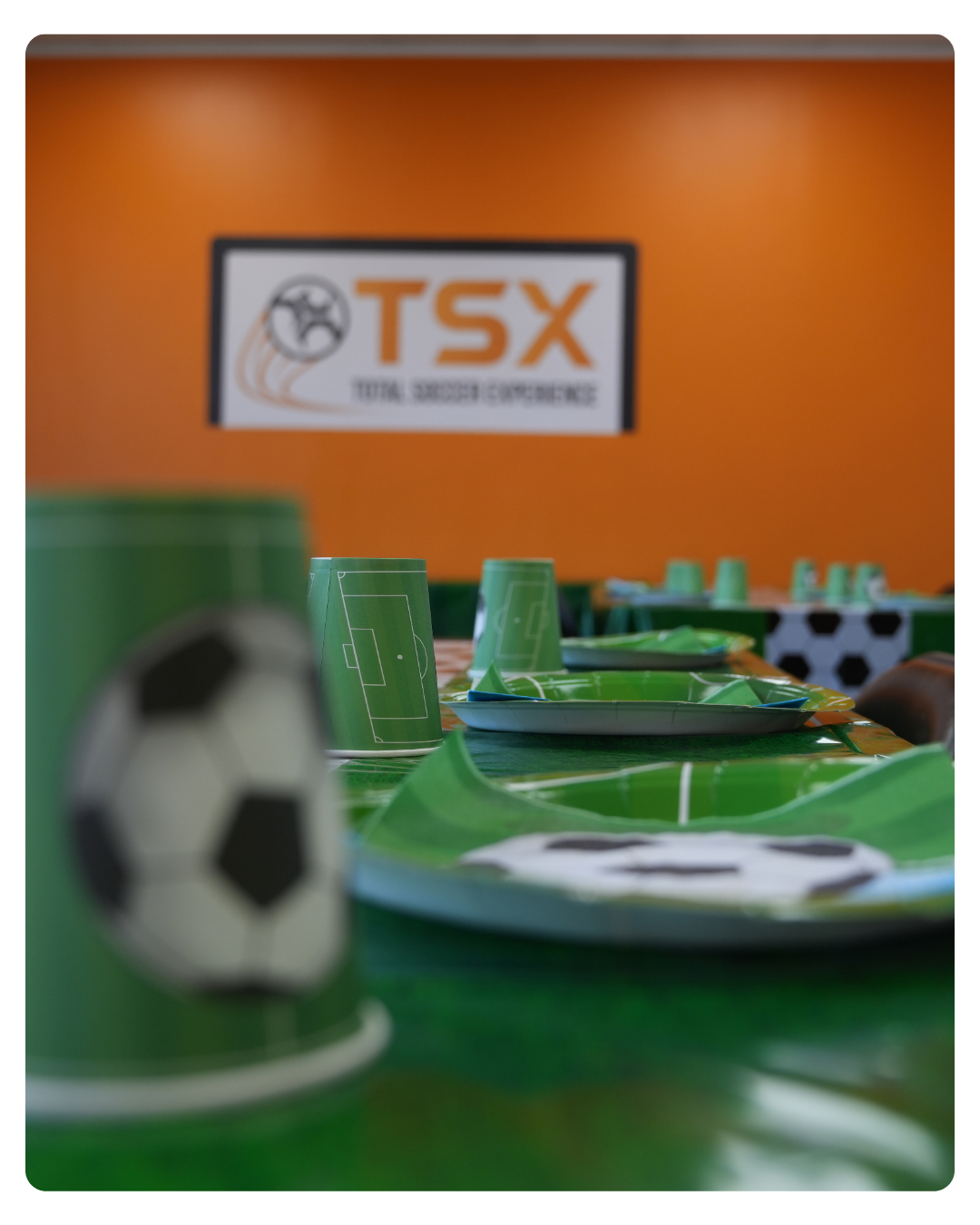 Total Soccer Children's table setting with soccer-themed plates, cups, and napkins in front of a TSX sign.