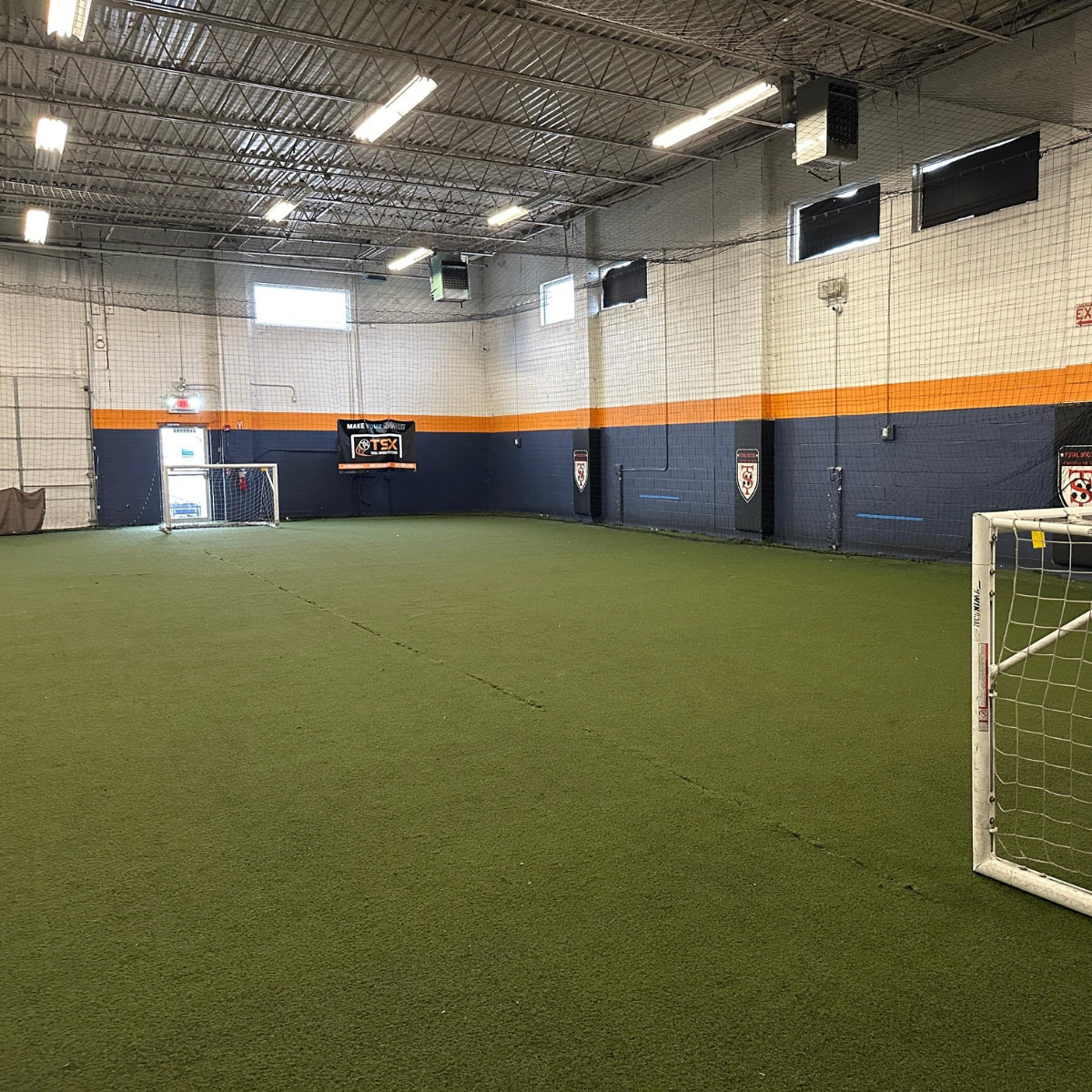 Indoor sports facility with green artificial turf and sports equipment.