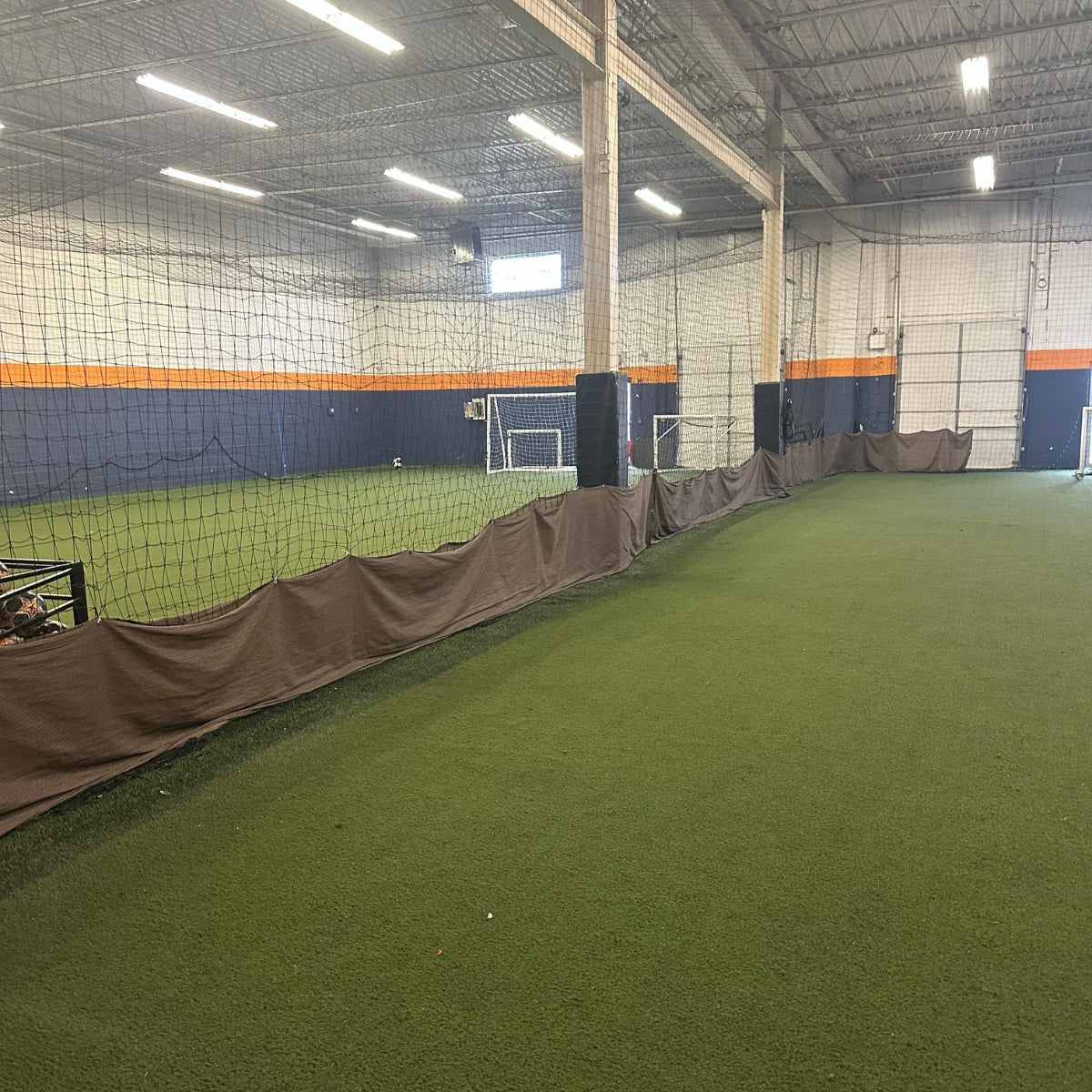 Total Soccer Indoor sports facility with green artificial turf and netting on the walls.