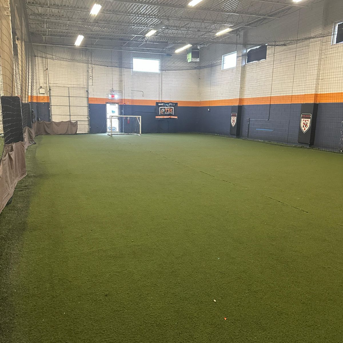 Total Soccer Indoor sports facility with artificial grass flooring and sports equipment.