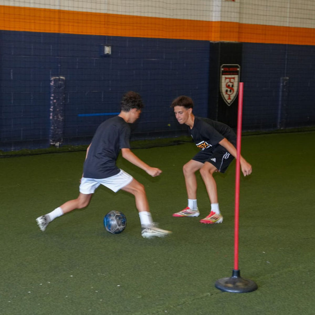 Total Soccer kids playing soccer indoors with a ball and goalpost.