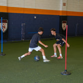Total Soccer kids playing soccer indoors with sports equipment on a green field.
