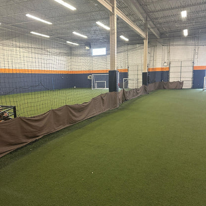 Total Soccer Indoor sports facility with green artificial turf and netting on the walls.