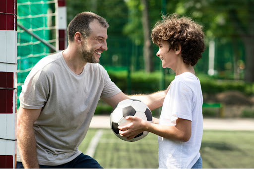 parent smiling at child holding soccer ball