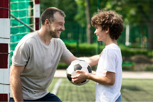 parent smiling at child holding soccer ball