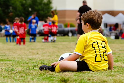 child sitting on soccer field